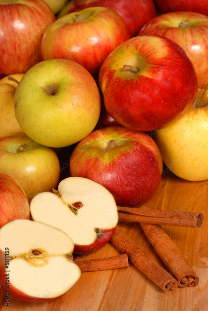 Apples on a table with one cut in half with cinnamon sticks Apples on a table with one cut in half with cinnamon sticks