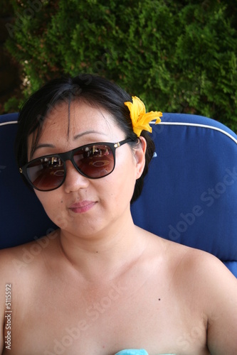 Asian woman with sun-glasses and flower in her hair