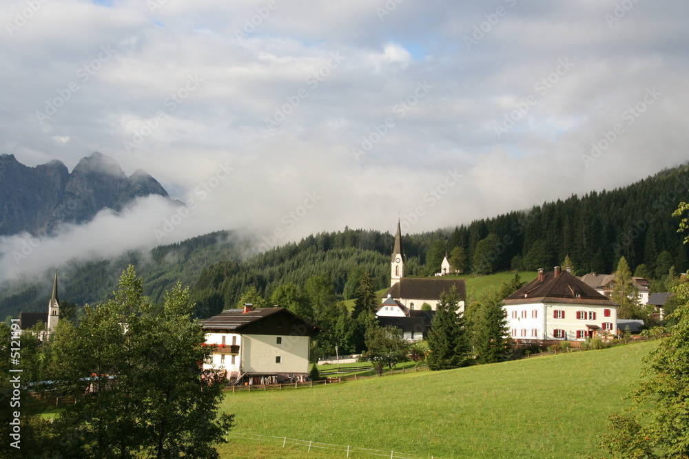 Meadow in the high mountains with houses, trees and church