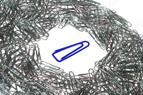 Big isolated blue macro paper clip surrounded by many little