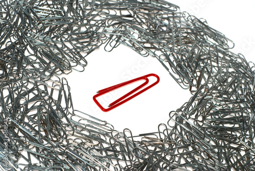 Big isolated red macro paper clip surrounded by many little