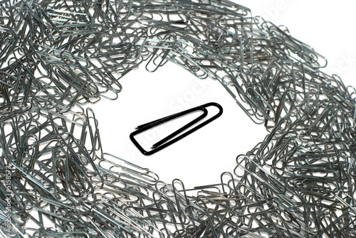Big isolated black macro paper clip surrounded by many little