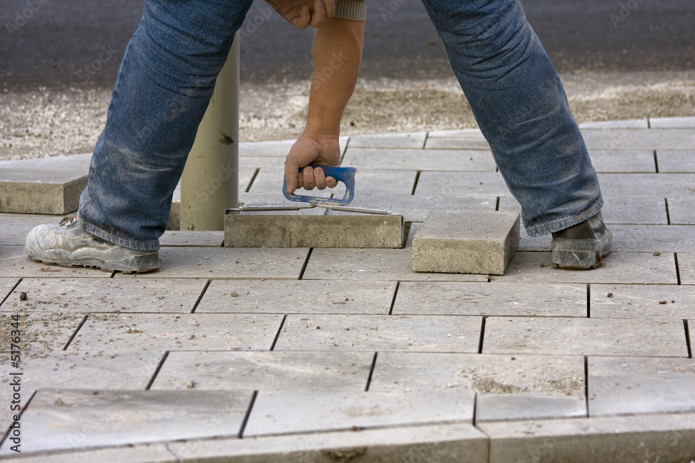 Arbeiter verlegt Gehwegplatten Arbeiter verlegt Gehwegplatten