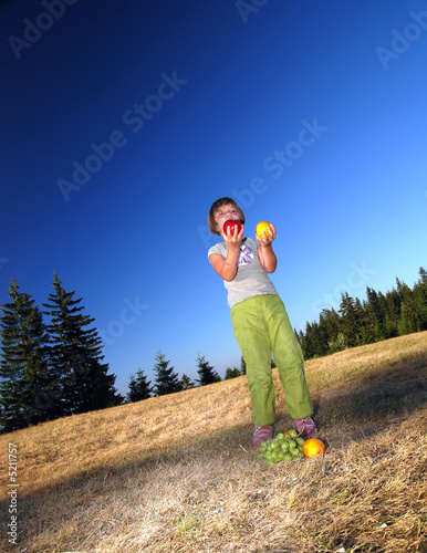 happy girl throwing apple outside photo