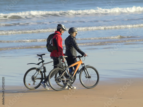 Pareja con bicicletas paseando por la playa