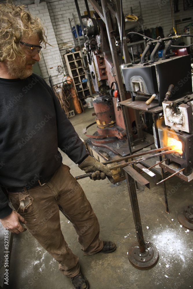 Metalsmith heating metal in forge. Metalsmith heating metal in forge.