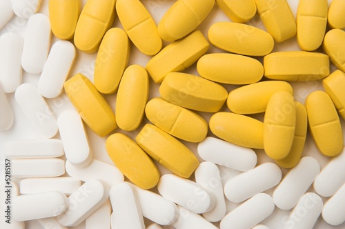white and yellow pills over black background