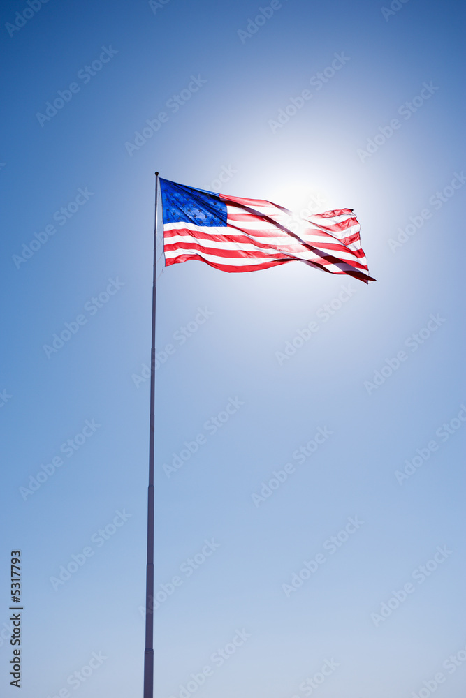 American flag blowing in clear blue sky.