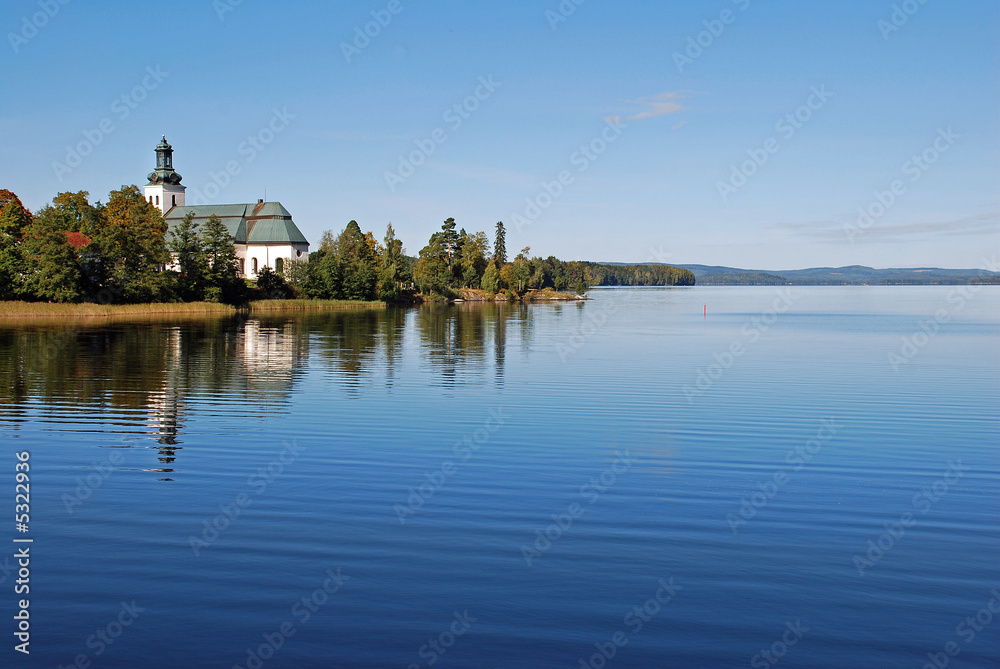 Reflection of sky and church on placid lake in Sweden