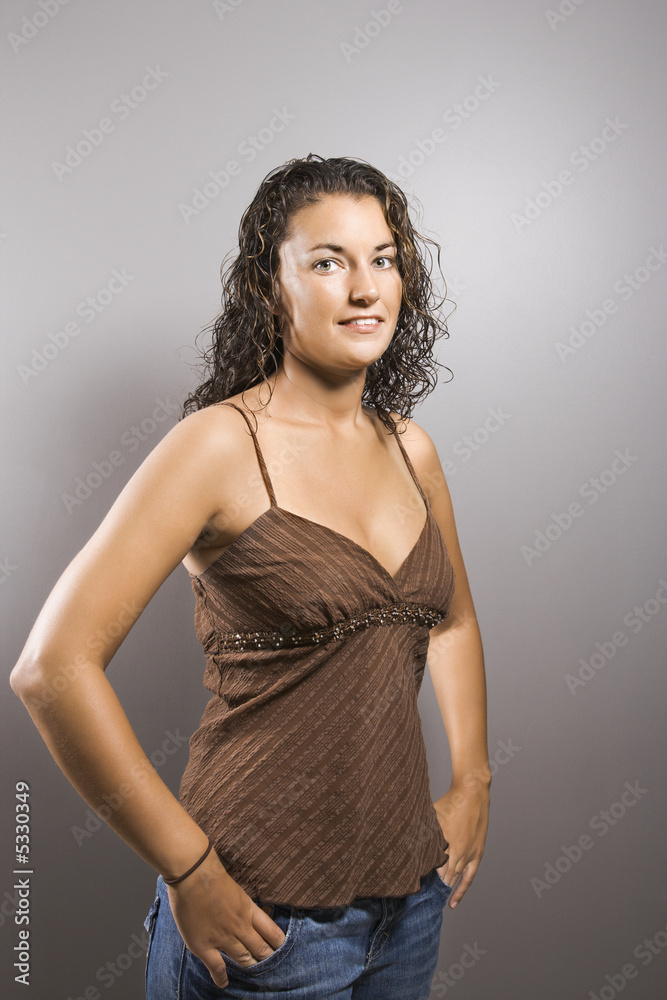 Portrait of brunette female with fingers in pockets smiling. Portrait of brunette female with fingers in pockets smiling.