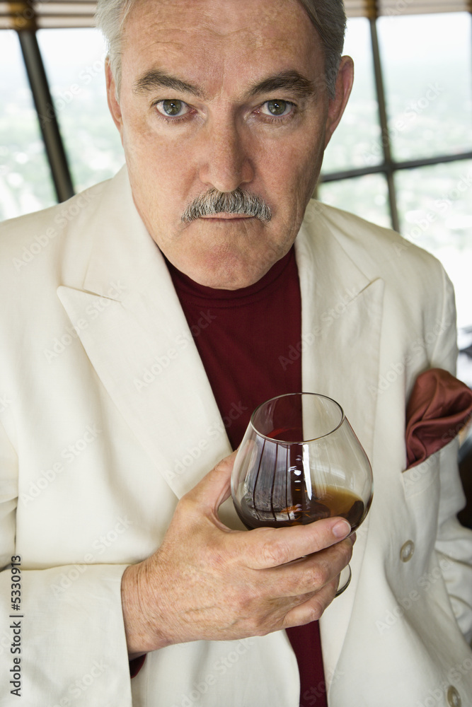 Mature Caucasian man in suit holding snifter of brandy. Mature Caucasian man in suit holding snifter of brandy.