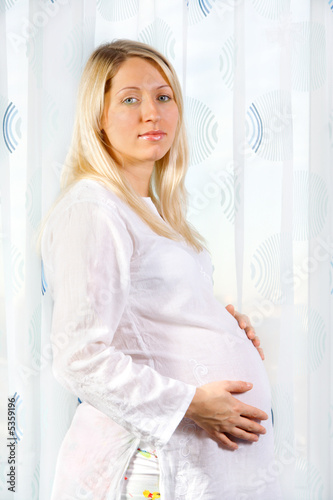 Pregnant woman standing and looking at camera