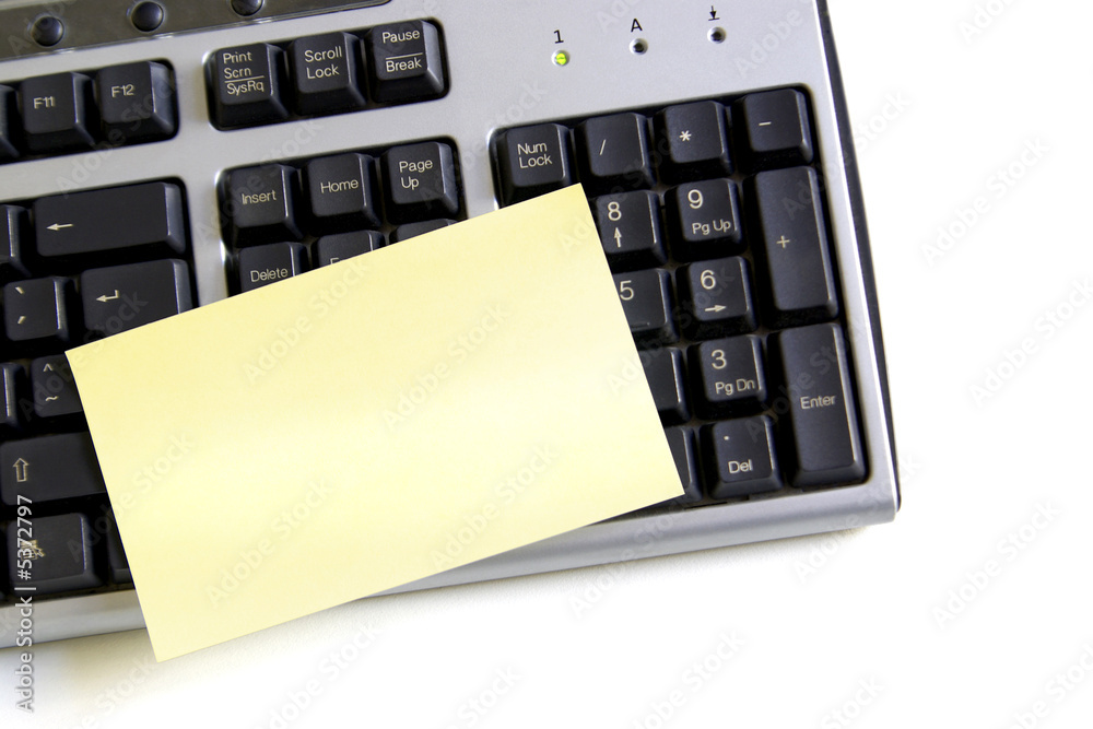 Close up of a computer keyboard and yellow post-it Close up of a computer keyboard and yellow post-it