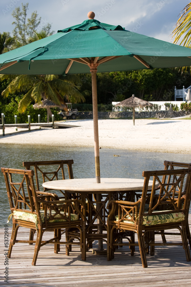 table and chairs with sun awning by sandy beach