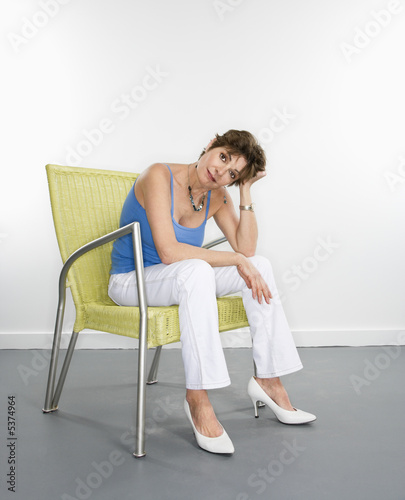 Portrait of pretty Caucasian woman sitting in modern chair.