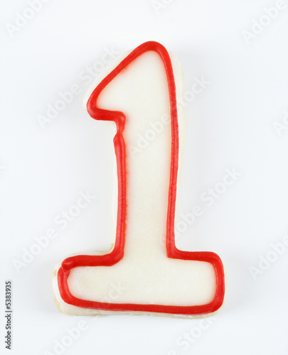 Sugar cookie in the shape of a number one outlined in red icing.