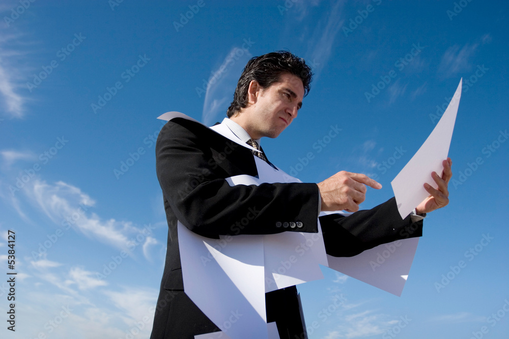 Businessman looking over paperwork with confused expression Businessman looking over paperwork with confused expression