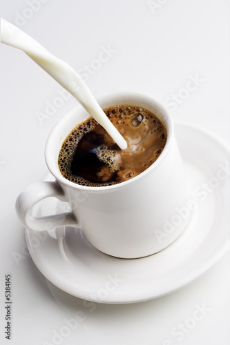 Pouring cream into a cup of coffee 