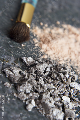Powder makeup and brush placed on a granite tabletop 