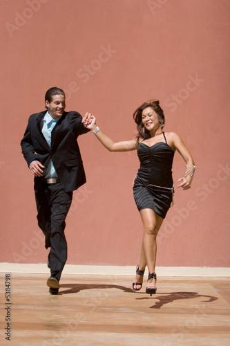 Happy attractive couple holding hands and running