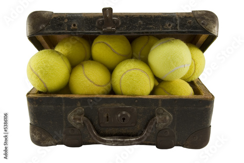 Old brown suitcase full of tennis balls isolated on white.