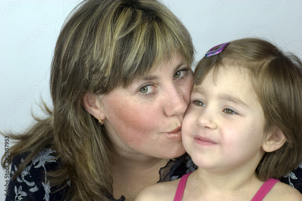 Middle aged mother kissing her little daughter