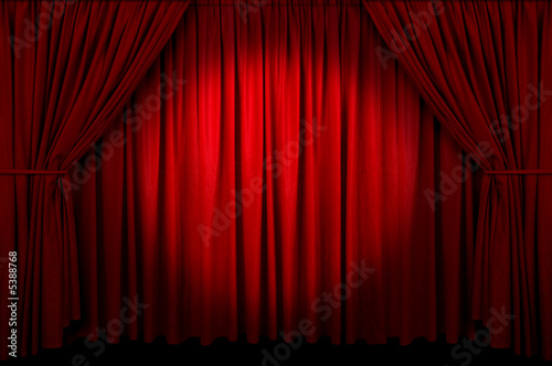 Large red curtain with spot light and fading into dark. photo