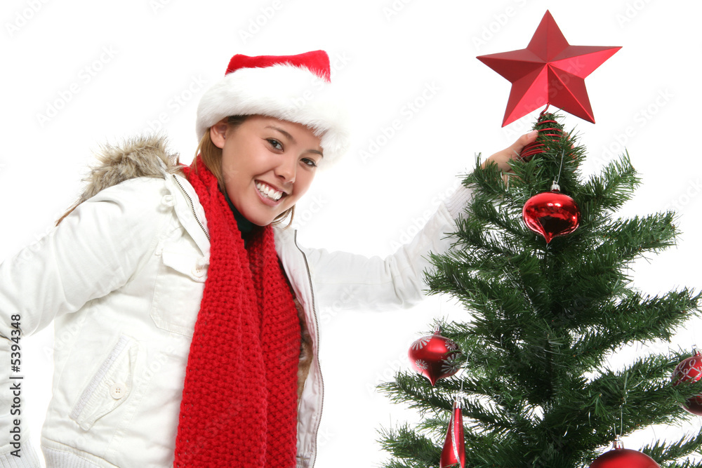A pretty woman putting a star on the Christmas tree