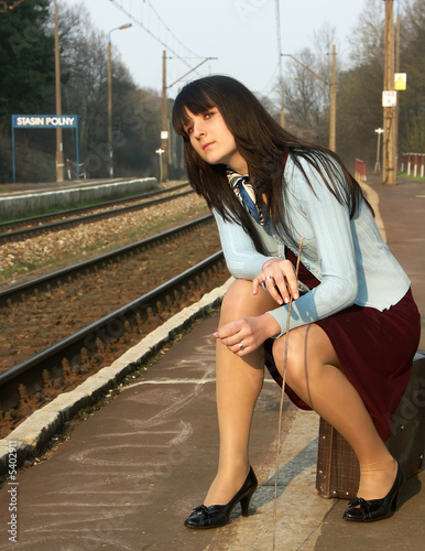 Young girl waiting for the train on the empty railway platform
