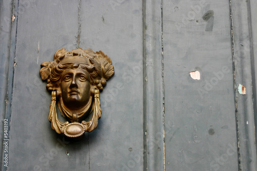 Old door knocker on old painted wall.