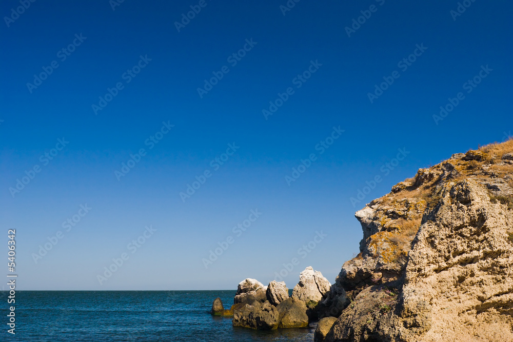 seascape with blue sky and brown sandstone rock