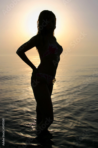 Woman silhouette on the beach at sunrise