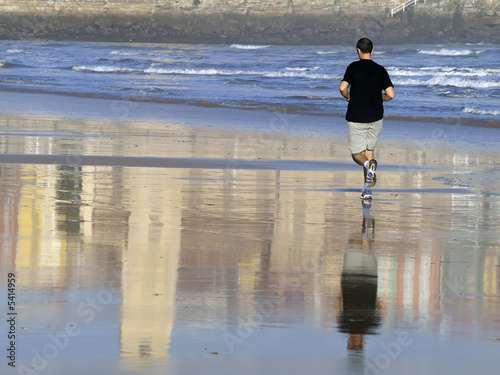 Hombre corriendo por la playa photo