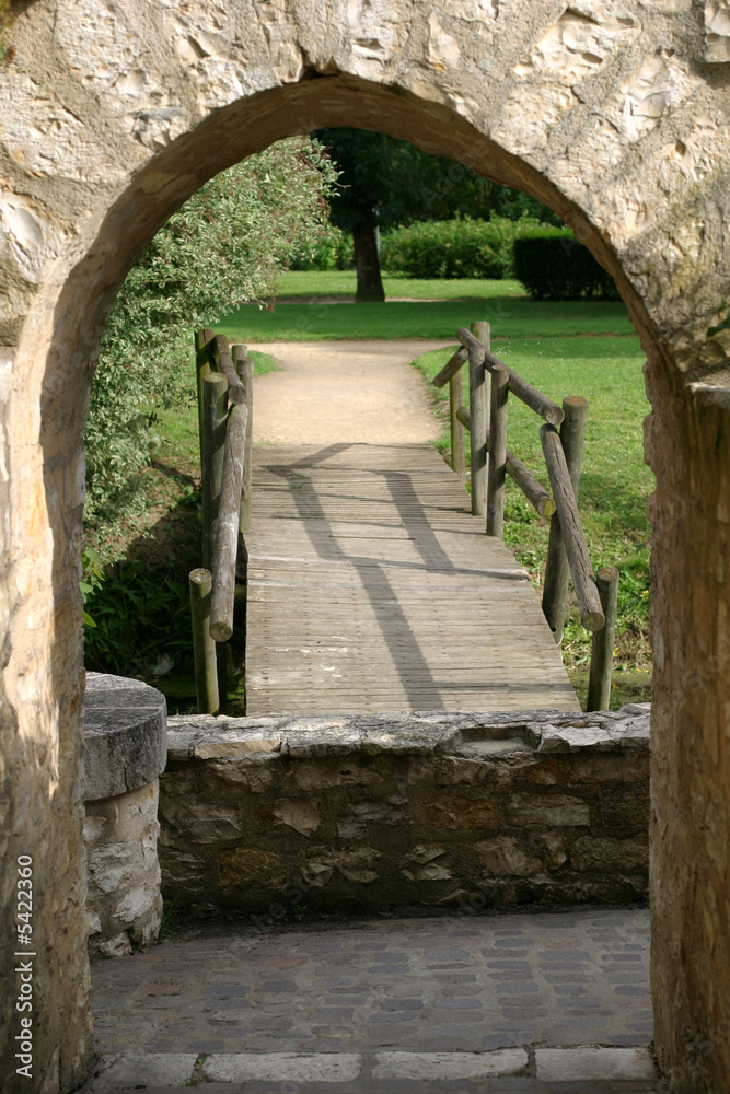 Garden Entrance - a bridge is framed by an arch in a French park