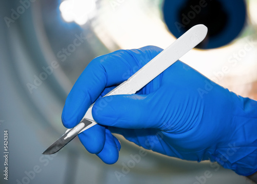 Fotografiet scalpel in surgeon's hand under lamp