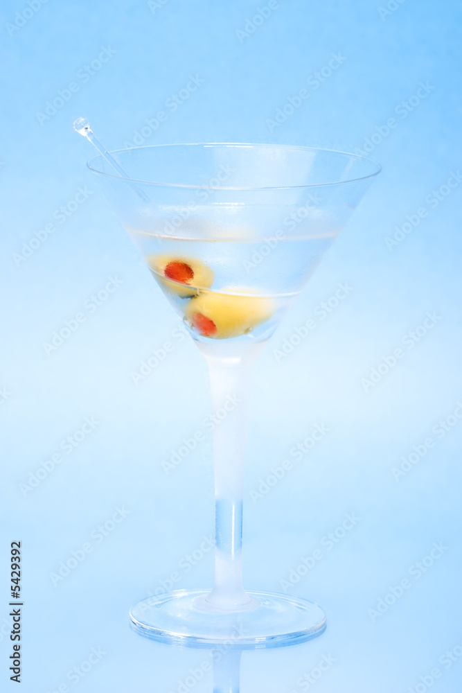 martini in glass with two olives over aqua background. martini in glass with two olives over aqua background.