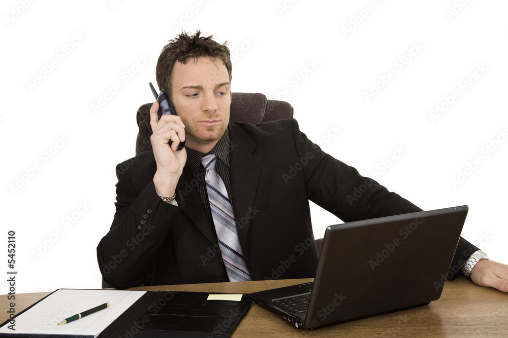Caucasian businessman setting a desk talking on the phone Caucasian businessman setting a desk talking on the phone