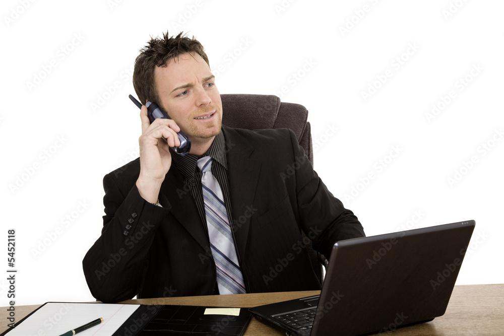 Caucasian businessman setting a desk talking on the phone Caucasian businessman setting a desk talking on the phone