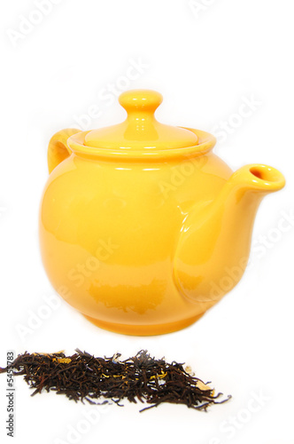 Yellow teapot with tea leaves isolated on white