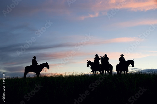 Cowboys silhouetted against a dawn sky. Montana horse ranch photo