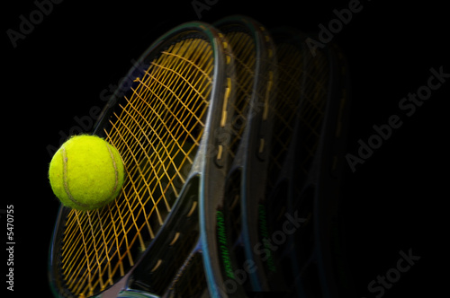 Tennis racket and ball on black background