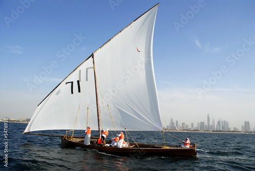 Arab Sailors On A Sailing Dhow And The Cityscape Of Dubai