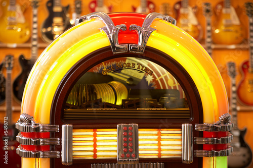 front view of a very colorful jukebox with guitars in the back photo