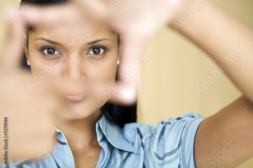 Businesswoman looking through frame made with her fingers