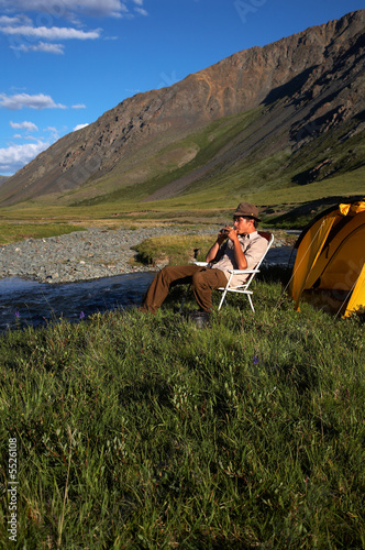 man at the camp in mountains near the stream