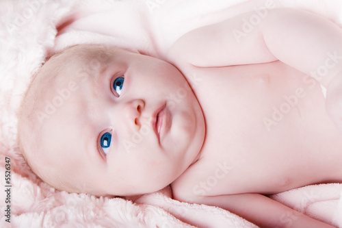 A blue eyed newborn on a pink blanket