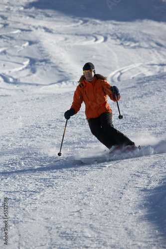 female skier on skiing track with powder in the background
