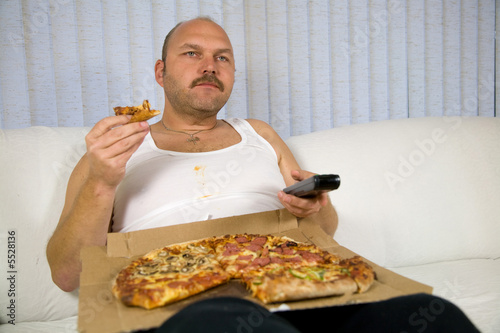 Overweight mature man sitting on the couch 