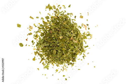 Dried, crushed parsley flakes isolated on white.