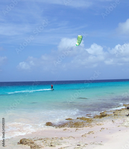 wind surfer glides along the ocean reef